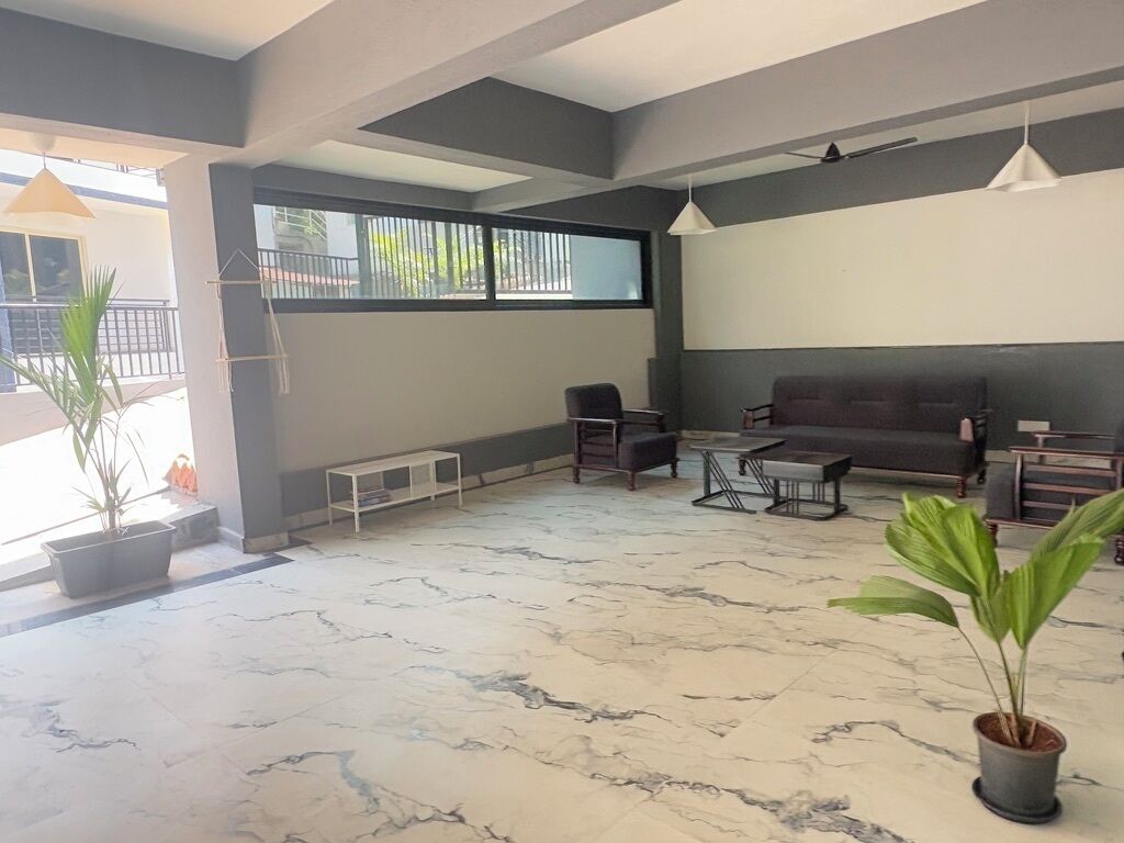 A spacious living area with a marble floor, a sofa, a coffee table, and potted plants.