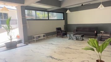 A spacious living area with a marble floor, a sofa, a coffee table, and potted plants.