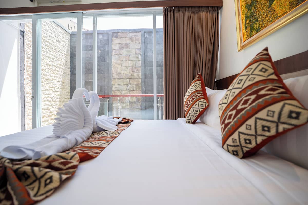 A hotel room with a large bed, a view of a stone wall and a balcony.
