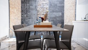 A modern dining area with a marble table, leather chairs, a vase with dried plants, and a water bottle. - Lumbung Sari Studio (Kuta)