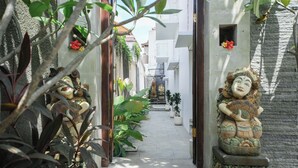 A narrow alleyway with traditional statues and potted plants. - Lumbung Sari Studio (Kuta)