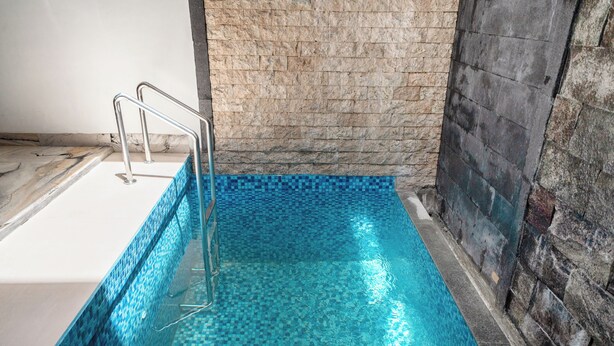 A swimming pool with a tiled floor and a metal ladder. - Lumbung Sari Studio (Kuta)