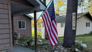A house with a porch, an American flag, a mailbox, and a number 9219 sign on a tree.