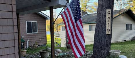 A house with a porch, an American flag, a mailbox, and a number 9219 sign on a tree.