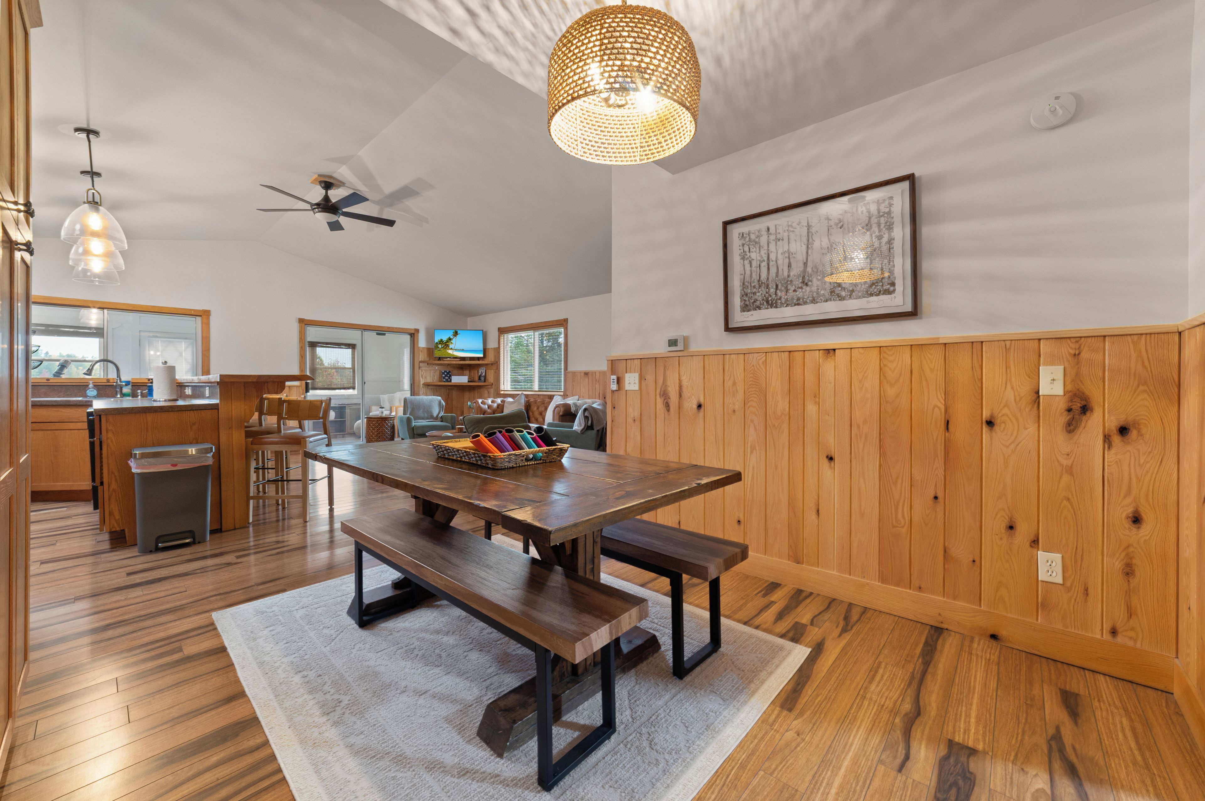 Une cuisine spacieuse avec des meubles de rangement en bois, une table à manger avec des bancs et un ventilateur de plafond.