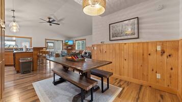 Une cuisine spacieuse avec des meubles de rangement en bois, une table à manger avec des bancs et un ventilateur de plafond.