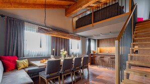 Ein modernes Interieur mit Essbereich, Küche und einer Holztreppe.