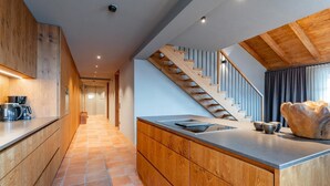 Eine moderne Küche mit Holzschränken, einer zentralen Kochinsel und einer Treppe, die in einen oberen Bereich führt.