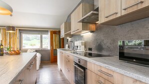 A modern kitchen with wooden cabinets, a large island, stainless steel appliances, and a view of greenery outside. - Group house in Fügen , Zilltertal Arena (Fügen im Zillertal)