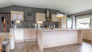 A modern kitchen with wooden cabinets, a built-in island, and a large window providing natural light. - Group house in Fügen , Zilltertal Arena (Fügen im Zillertal)