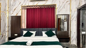 A hotel room with a marble wall, a large bed with green and white bedding, a red curtain, and a mirror above the bed. - KWIK STAY Tapovan (Rishikesh)