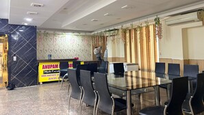 A conference room with a glass table and black chairs, a reception desk with a sign for breakfast and juices, and a decorative wall with hanging plants. - KWIK STAY Tapovan (Rishikesh)