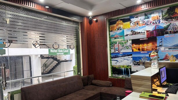 A hotel reception area with a sofa, a desk with a computer, and a wall decorated with pictures of tourist destinations. - KWIK STAY Tapovan (Rishikesh)