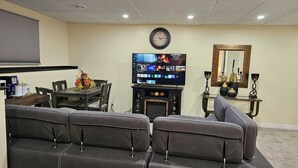 Een woonkamer met een flatscreen televisie, een open haard, een eettafel en een bank.