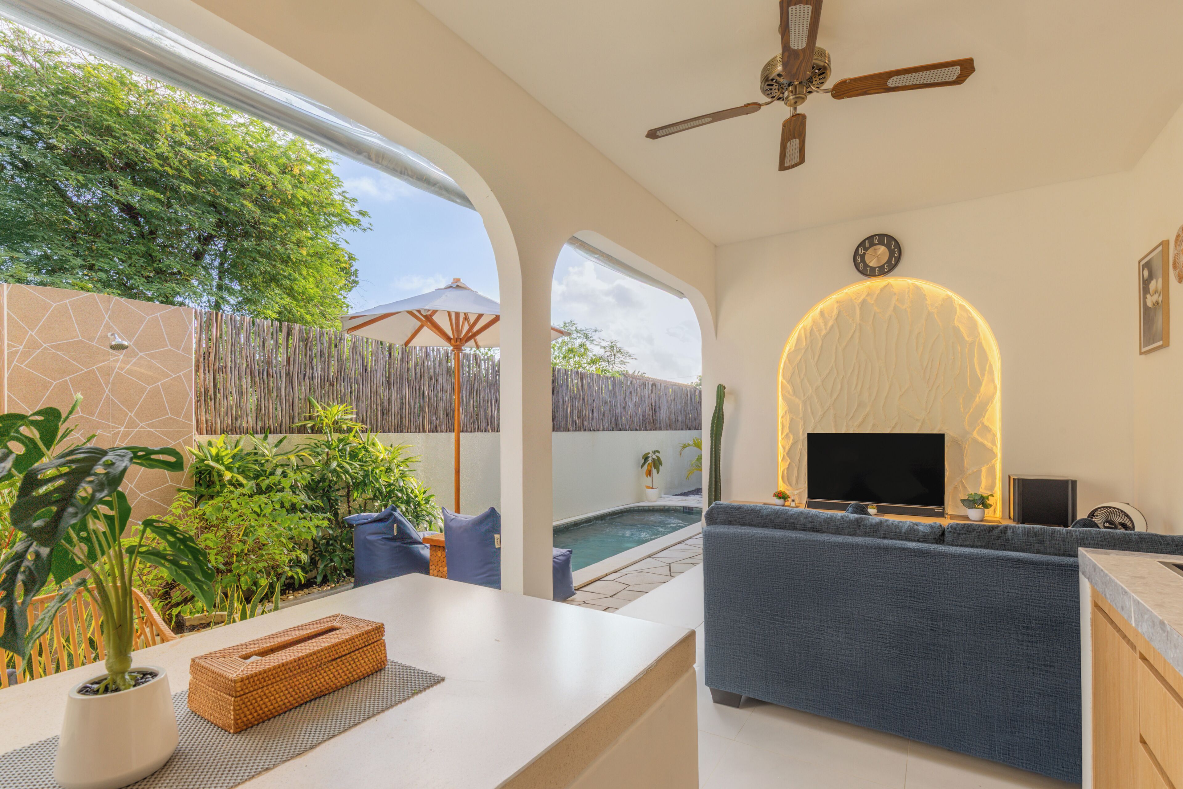 A modern living room with a pool, a ceiling fan, and a TV.