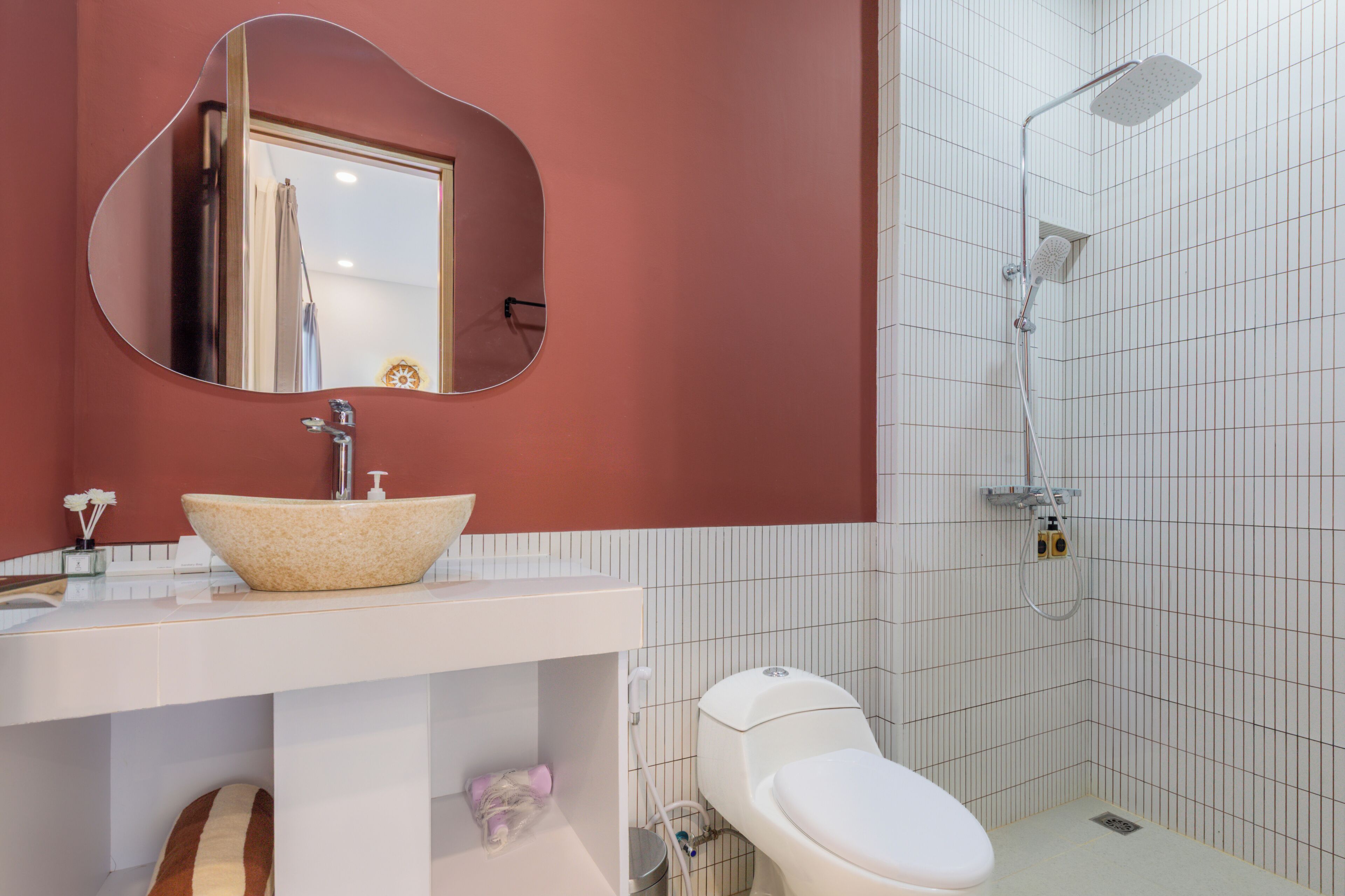 Et badeværelse med hvid vask, toilet, bruser og spejl.