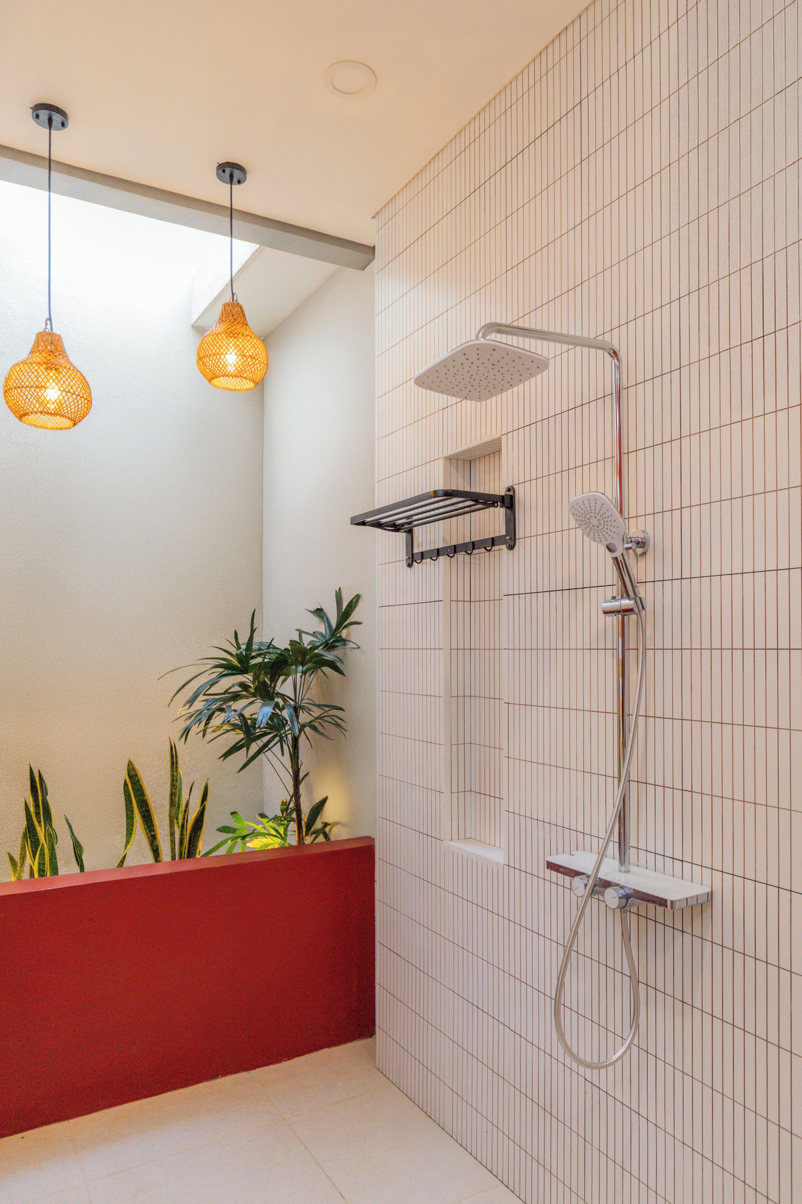 A modern bathroom with a shower, pendant lights, and a red accent wall.