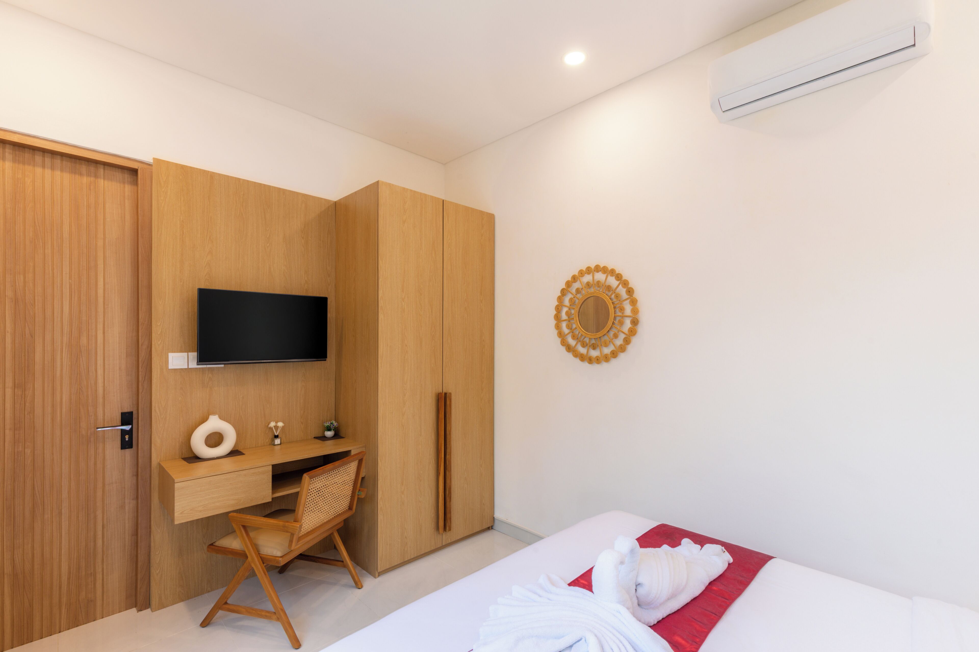 A bedroom with a bed, a desk, a chair, a TV, and a wardrobe.