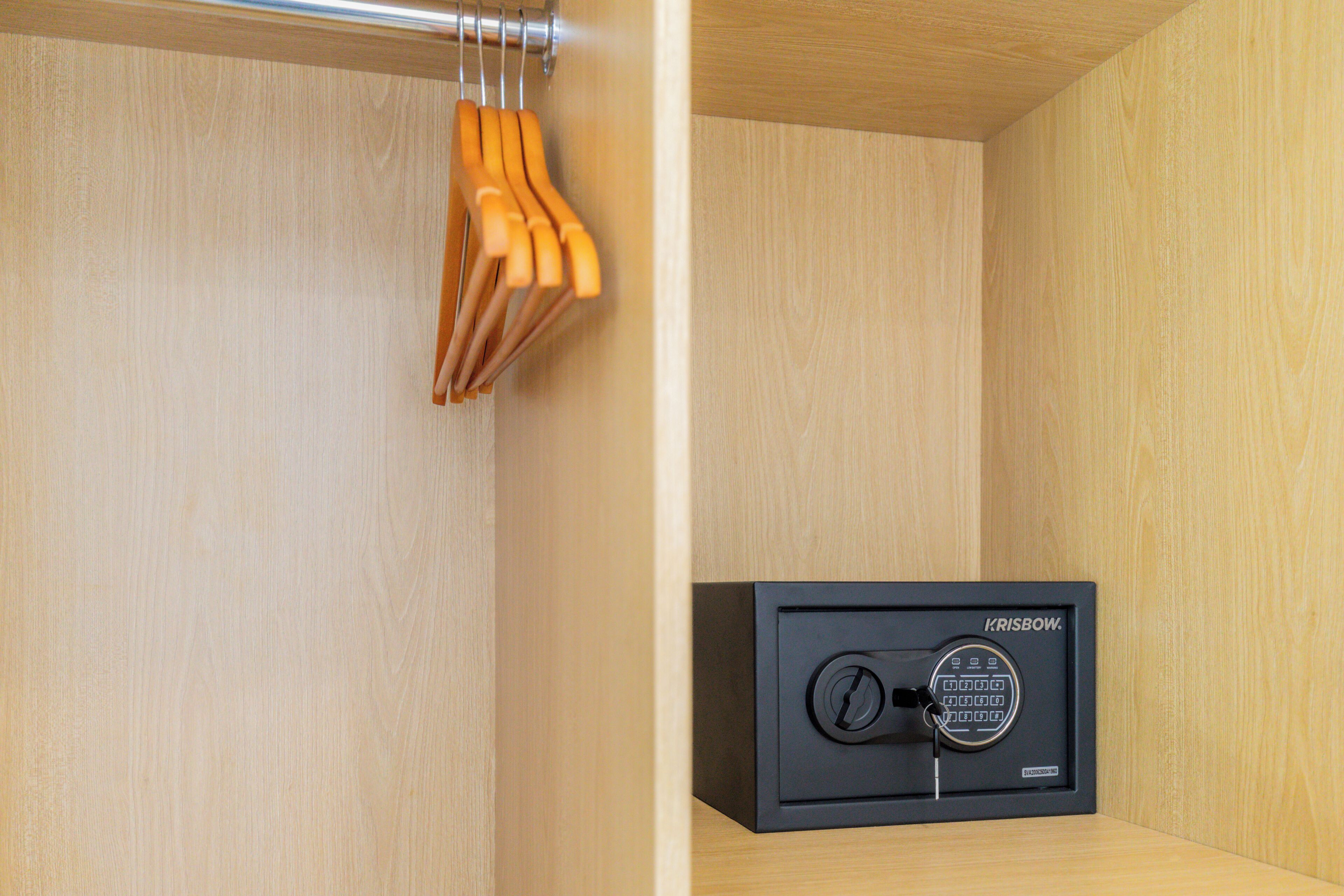 A wooden closet with a black safe and wooden hangers.