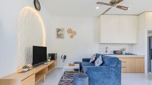 Una sala de estar moderna con una televisión de pantalla plana, un sofá, una mesa de centro y una cocina al fondo.