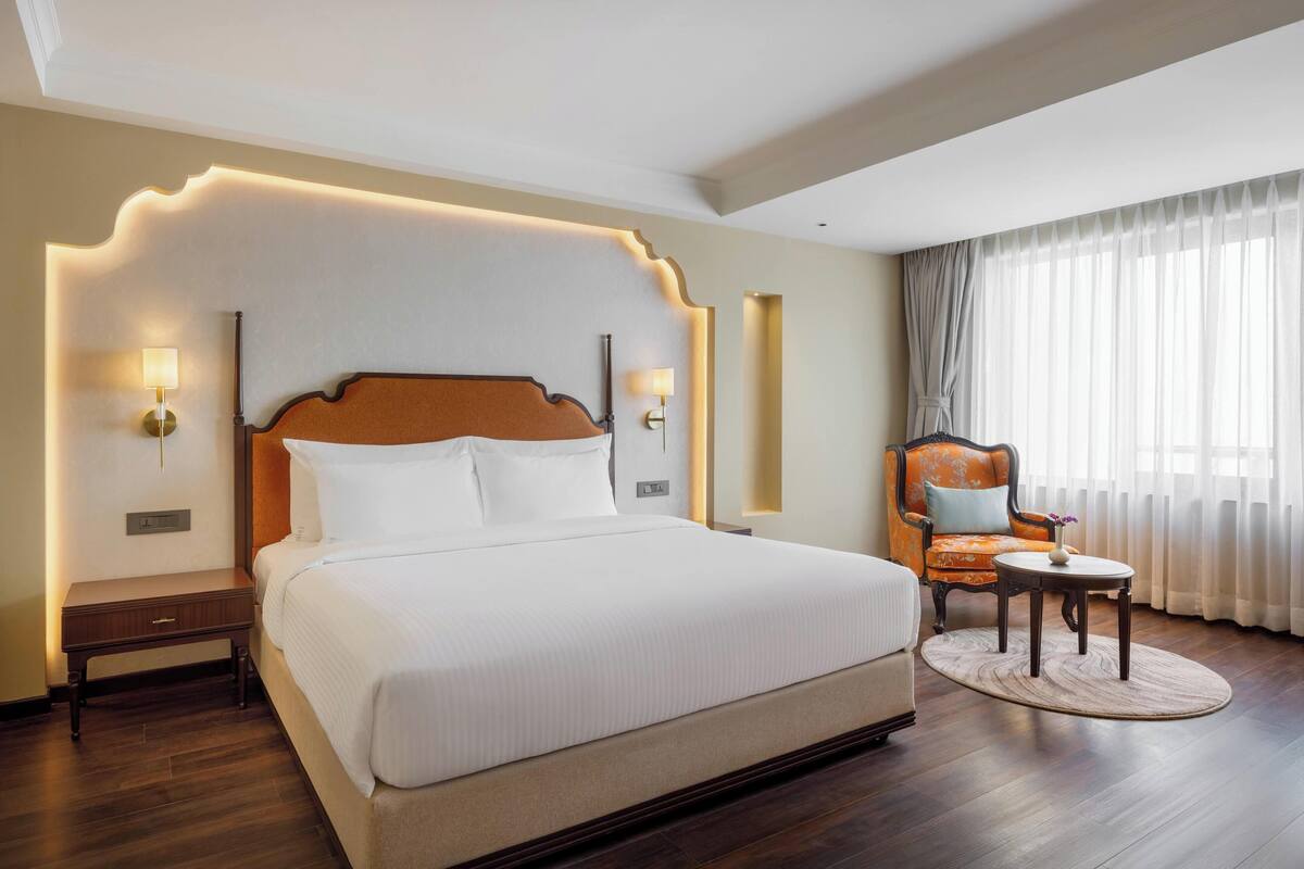 Una habitación de hotel con una cama grande, una mesita de noche, una silla y una pequeña mesa.
