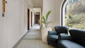 A hallway with a patterned floor, a large potted plant, and a dark leather sofa. - Bhangeri Durbar Resort (Baluwapati Deupur)