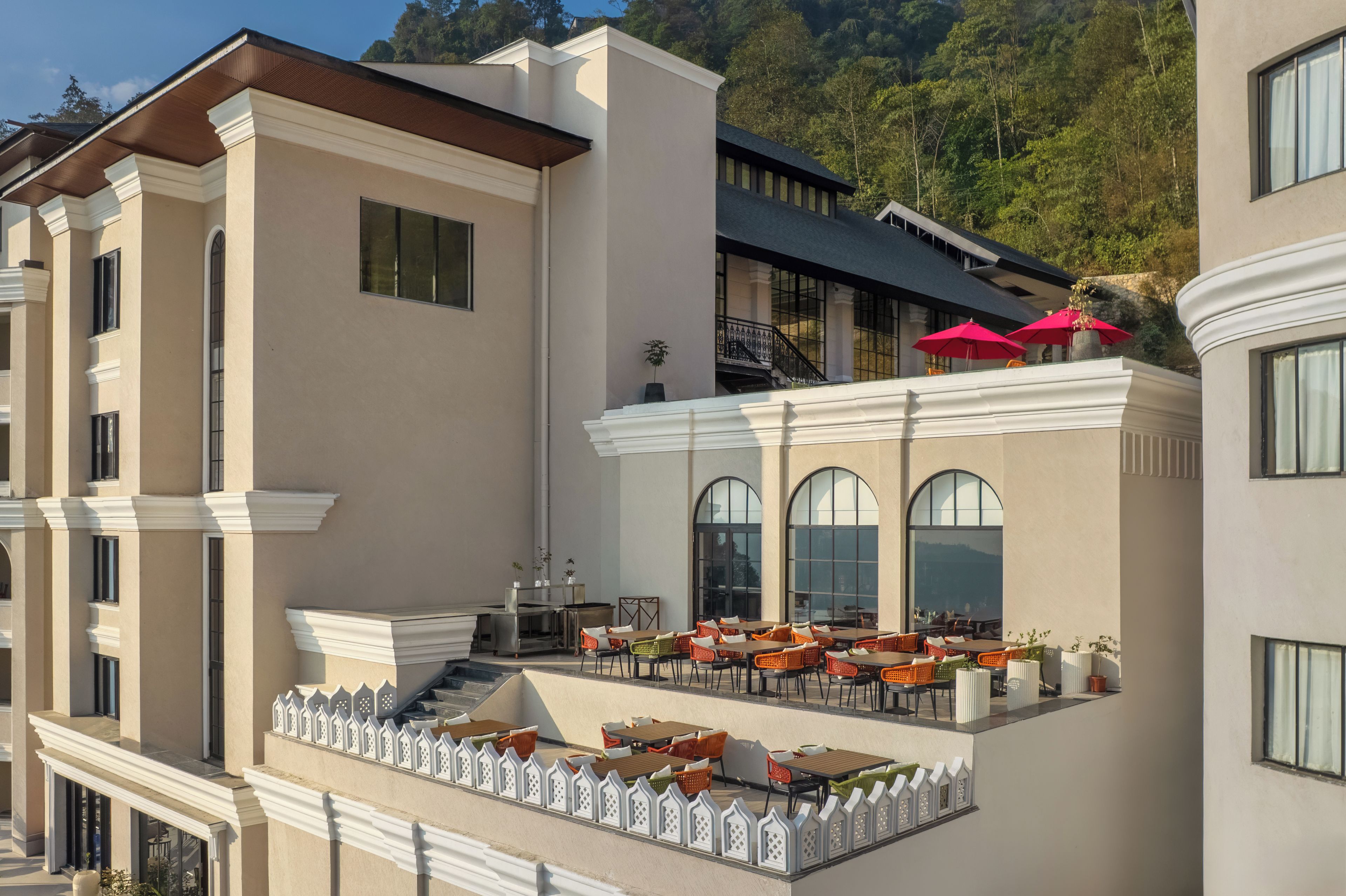 A hotel with outdoor seating, a staircase, and a view of the surrounding landscape.