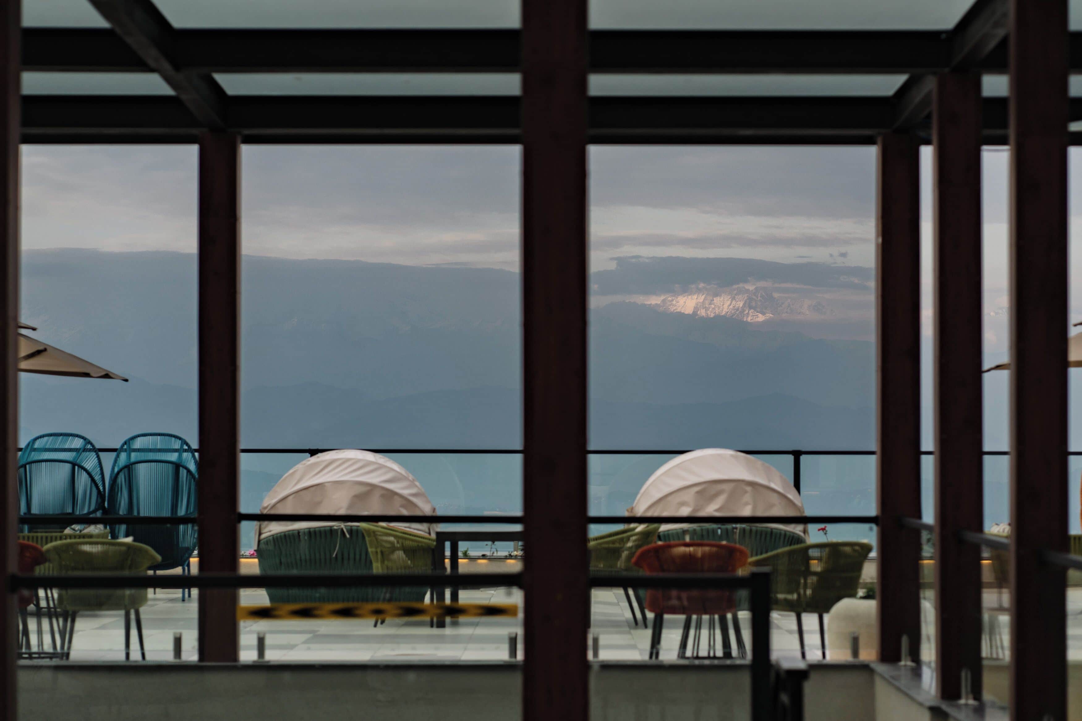 A terrace with tables and chairs, overlooking a mountainous landscape.