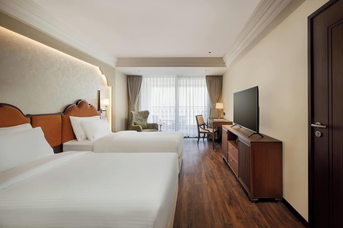 Una habitación de hotel con dos camas, televisión, escritorio y una silla.