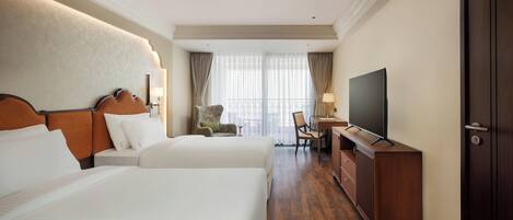 Una habitación de hotel con dos camas, televisión, escritorio y una silla.