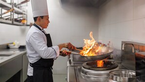 Een kok kookt met vlammen in een professionele keuken.
