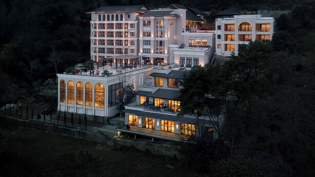 Een meerlaags hotel met een modern architectonisch ontwerp, met meerdere balkons en grote ramen.