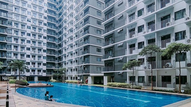 En moderne boligbygning med en central swimmingpool, altaner og en fliset gangsti.