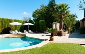 A swimming pool with lounge chairs and umbrellas, surrounded by well-maintained hedges and palm trees. - Stunning home in Arta with outdoor swimming pool (Arta)