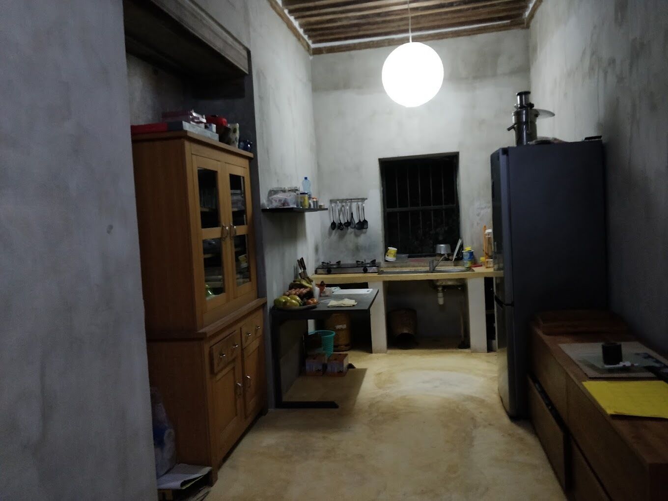 A compact kitchen with a wooden cabinet, a sink, and a refrigerator.