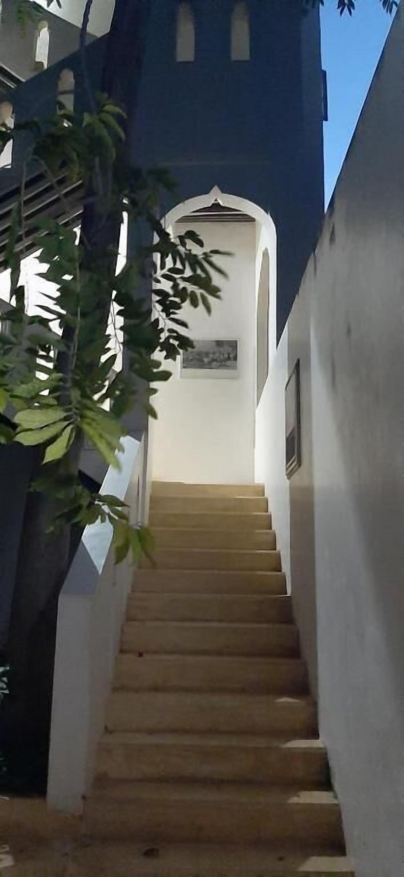 A staircase leading to a building with a white facade and a dark tower.