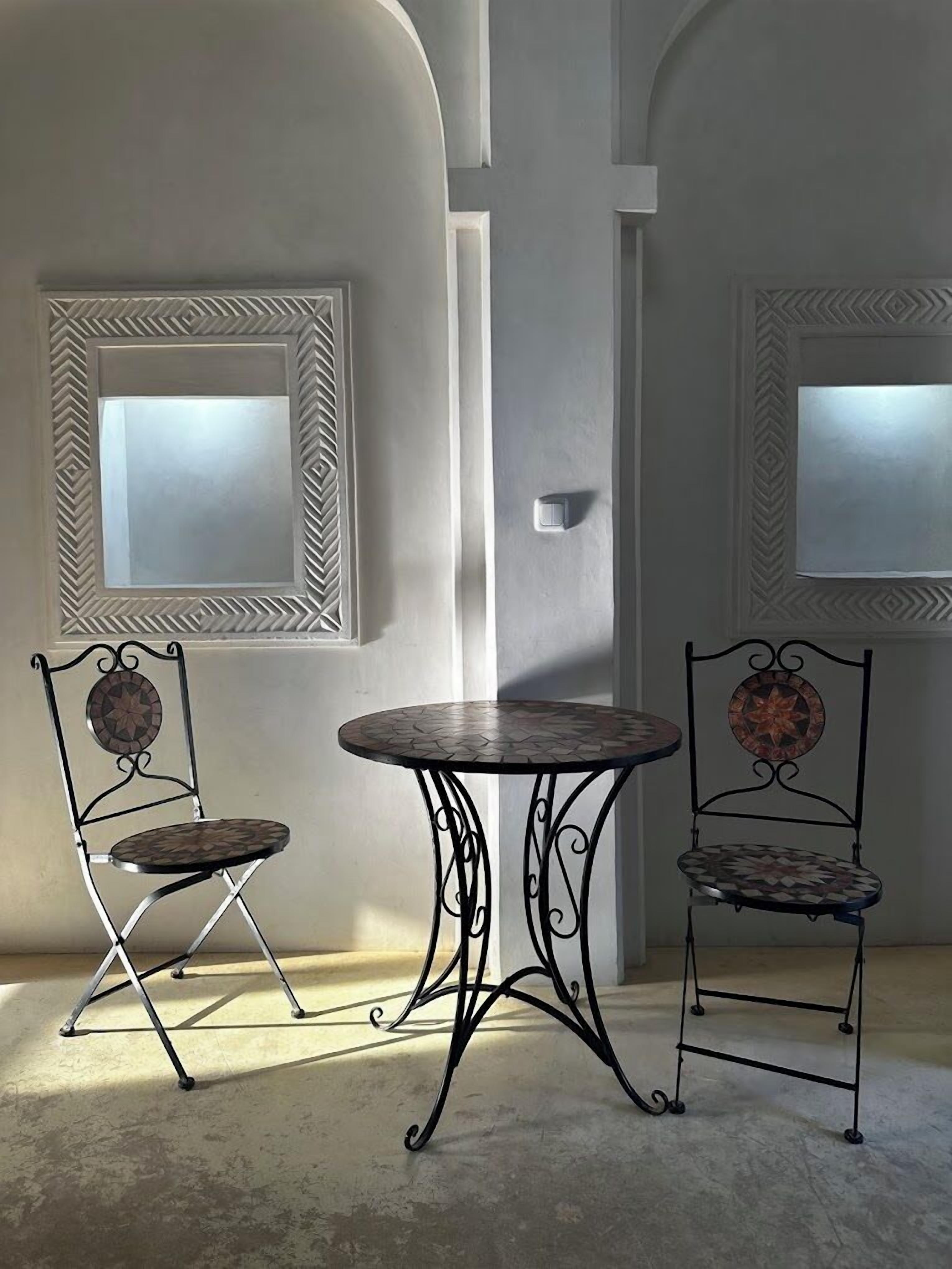 A room with a round table and two chairs with decorative backs.