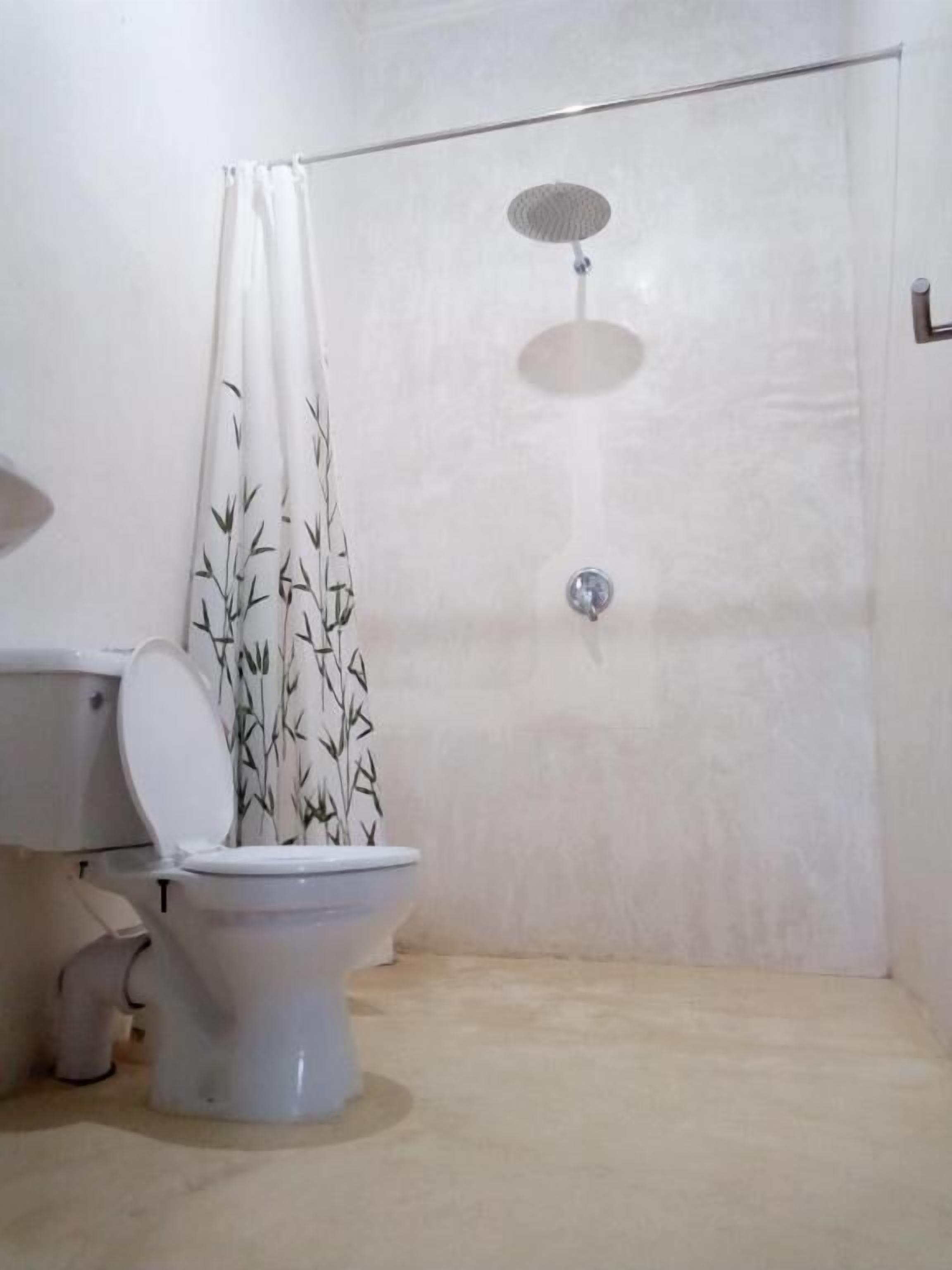 A bathroom with a toilet, a shower with a curtain, and a wall-mounted toilet paper holder.