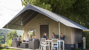 Un espace extérieur abrité, aménagé avec une table et des chaises, et entouré de verdure.