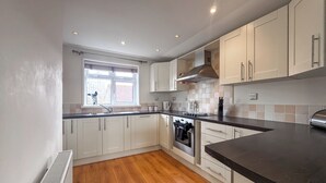 Una cocina moderna con armarios blancos, encimera negra y una ventana que proporciona luz natural.
