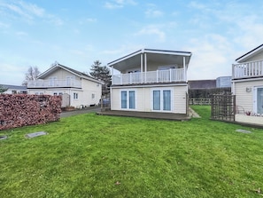 A row of mobile homes with a grassy yard and a wooden fence. - 3 bedroom accommodation in Wisbech (Wisbech)