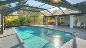 A covered swimming pool with a clear view of the surrounding landscape, including trees and a patio area with outdoor furniture. - Poolside Bliss! Port Charlotte Haven 4 Mi to Beach (Port Charlotte)