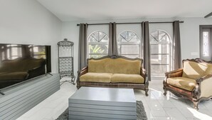 A living room with a sofa, armchair, and a flat-screen TV. - Poolside Bliss! Port Charlotte Haven 4 Mi to Beach (Port Charlotte)