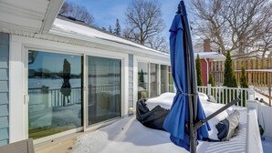 Eine überdachte Terrasse mit einer Schiebetür, einem blauen Sonnenschirm und Schnee auf dem Boden.