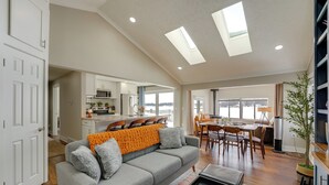 Ein geräumiger Wohnbereich mit grauem Sofa, Couchtisch und Essbereich inklusive Tisch und Stühlen.