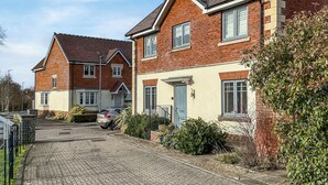 A residential street with houses, a paved driveway, and a parked car.
