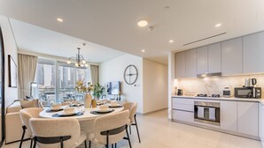 Una cucina moderna con elettrodomestici integrati, un'area pranzo con tavolo e sedie rotonde e un'ampia finestra che offre vista sulla città.