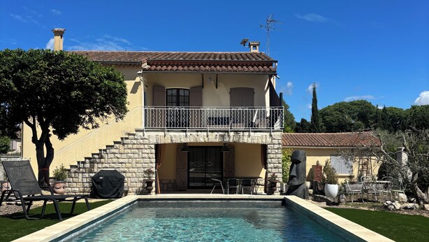 Una casa de dos pisos con piscina, escalones de piedra y mobiliario exterior.