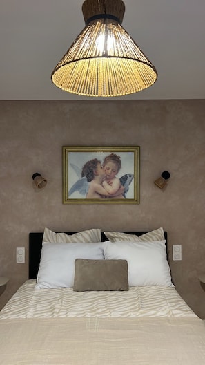 A bedroom with a bed, a hanging lamp, and a framed picture on the wall. - Cléandre - Self-contained apartment – Downtown Saint-Rémy (Saint-Rémy-de-Provence)