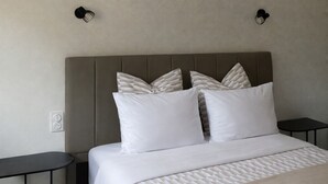 Una cama bien hecha con un edredón estampado, un cabecero y dos mesitas de noche con estructura negra.